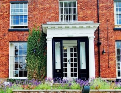 The front face of a large house with lawn in front.