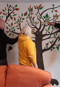 People looking at a tree mural on an interior wall.