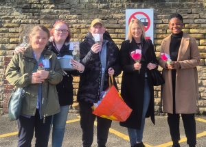 Group of peole outdoors with small posies to give away on mental heslth day.